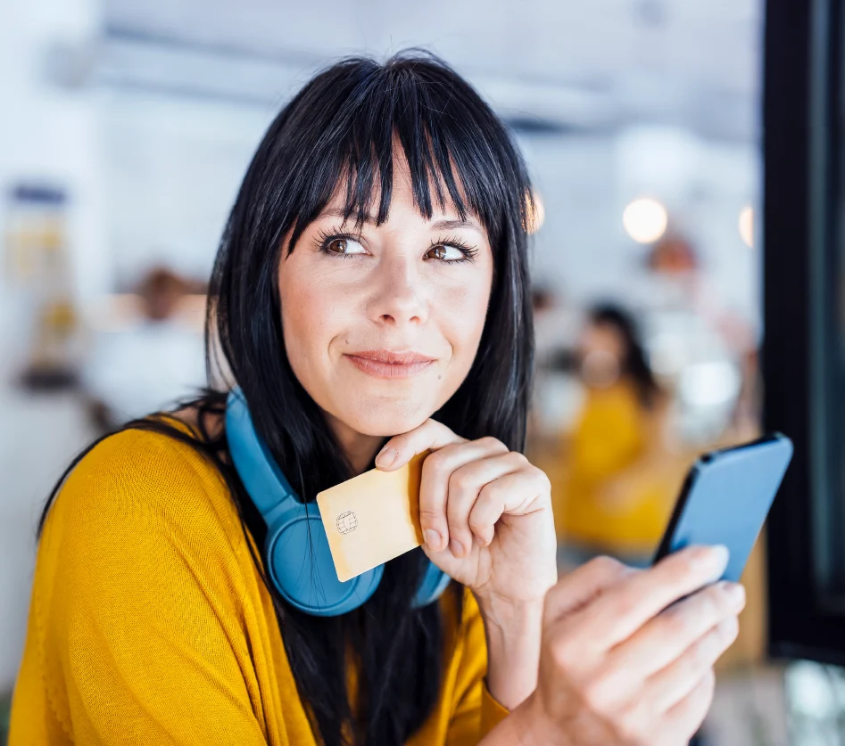 Woman holding a credit card while using her phone