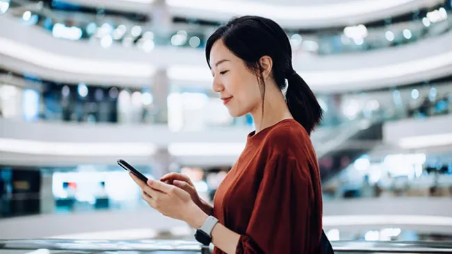 Woman looking at her phone while walking through a mall 