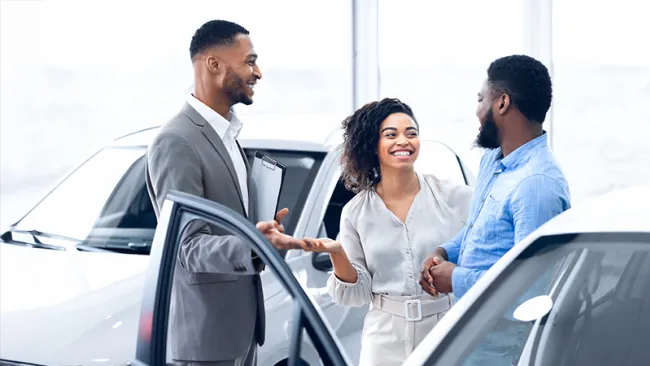 Three people talking in a car dealership