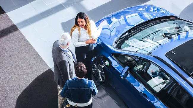 Three people talking beside a car