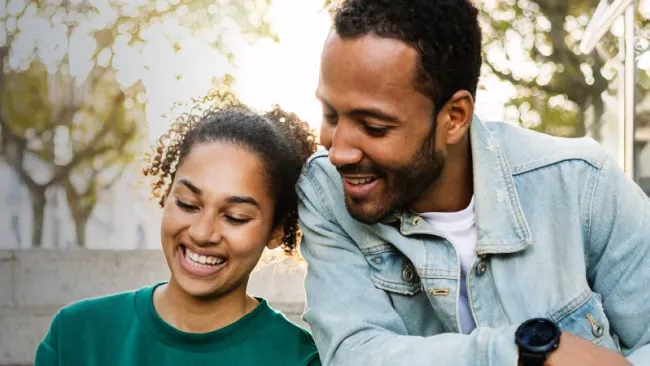 A couple smiling while sharing a phone screen