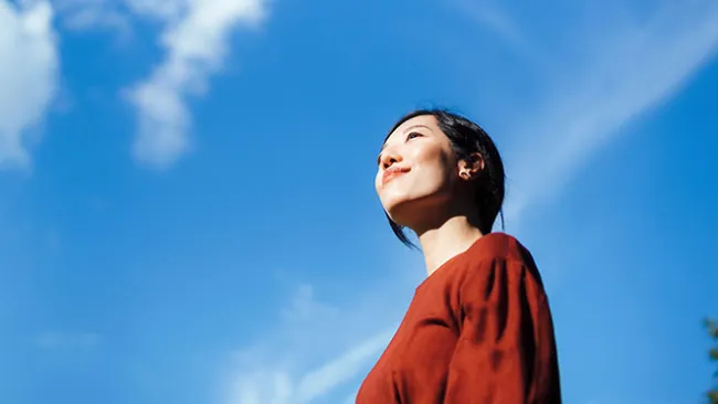 Woman looking up and smiling against a blue sky background