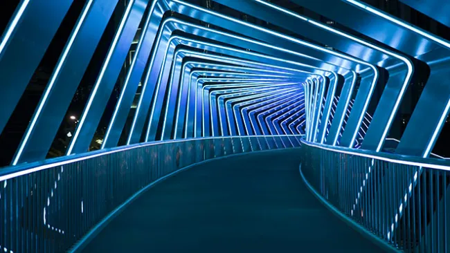 An illuminated pathway leading through a futuristic-looking tunnel 