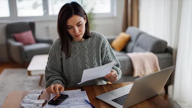 Woman looking at bills and her laptop