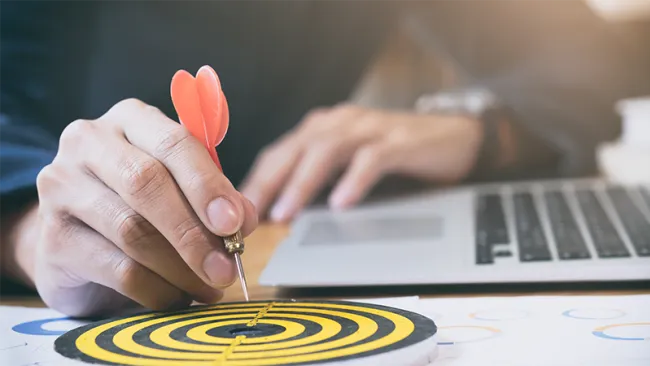 A hand placing a dart onto a target