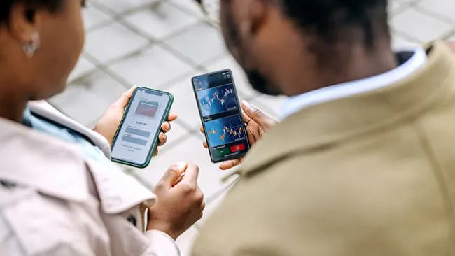 An over-the-shoulder view of two people looking at smartphones