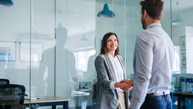 A man and a woman doing a handshake at the office