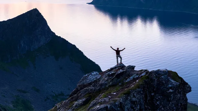Person standing on a mountaintop with arms outstretched