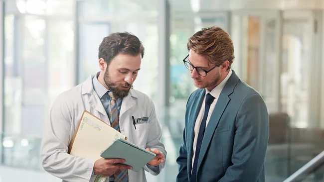 A healthcare professional showing another individual something on a tablet