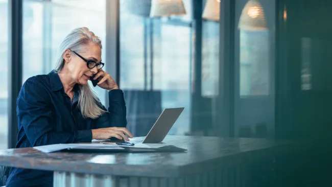 Woman on phone looking at a laptop