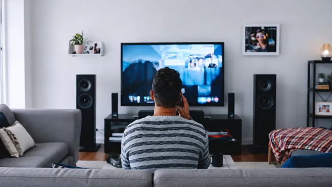 A man in a living room facing a large TV