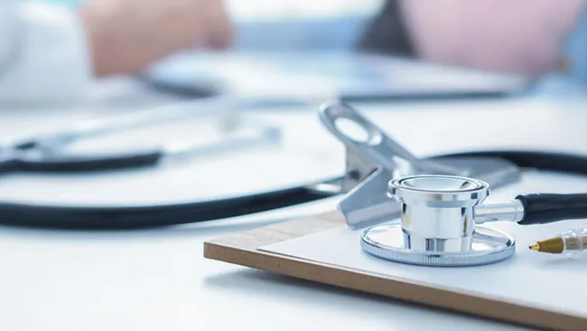 Stethoscope and clipboard sitting on a desk 