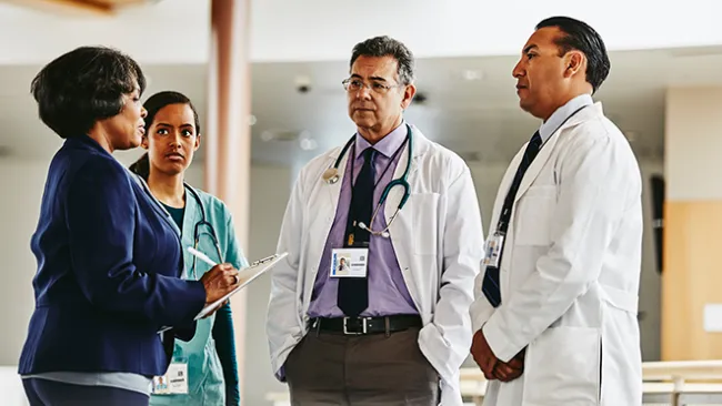 A female patient talking to two doctors and a nurse 