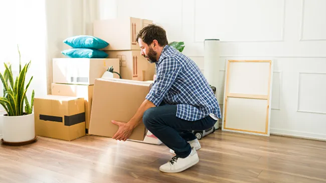 A man bending down to pick up a heavy box