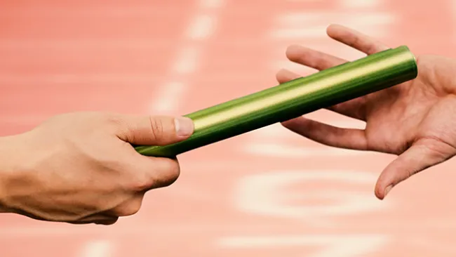 One person's hand handing a relay baton to another hand