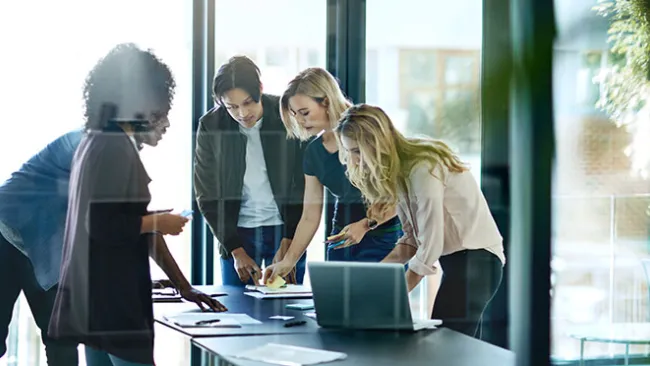 People standing around a desk, collaborating