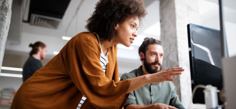 A woman discussing what's on the screen to her colleague