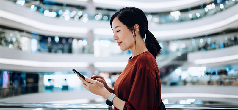 Woman looking at her phone while walking through a mall 