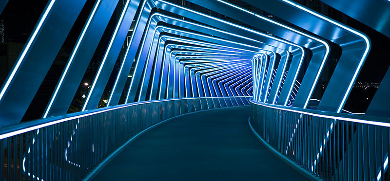 An illuminated pathway leading through a futuristic-looking tunnel 