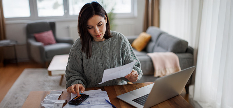 Woman looking at bills and her laptop