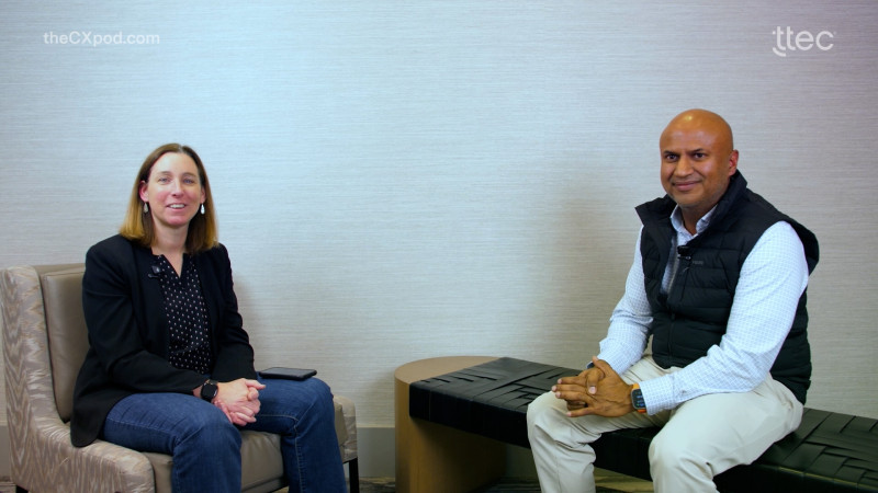 Two people sitting and smiling at a camera. Business setting. 