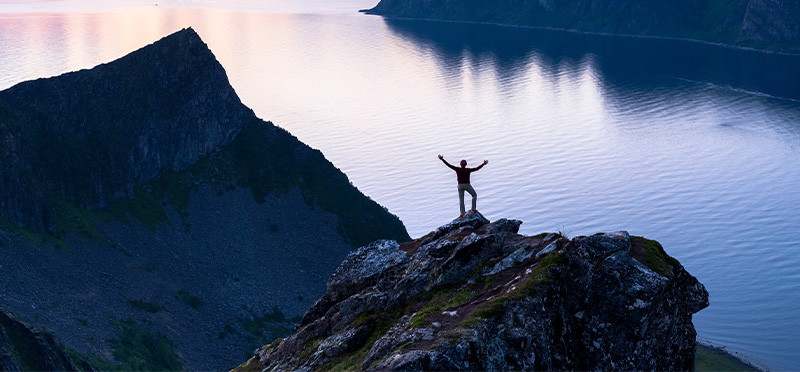 Person standing on a mountaintop with arms outstretched