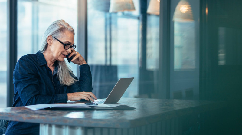 Woman on phone looking at a laptop