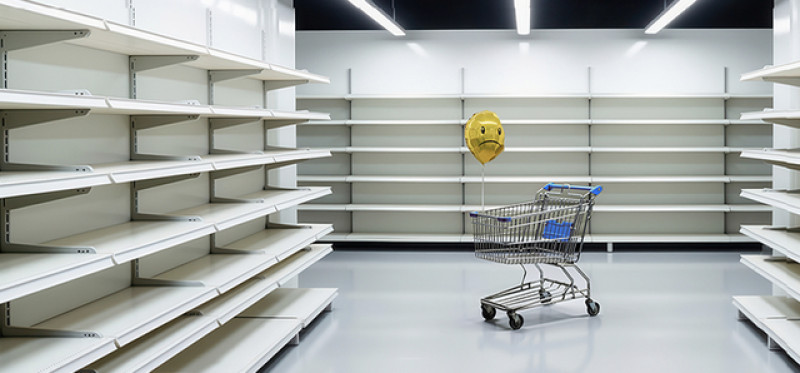 shopping cart among empty store shelves 