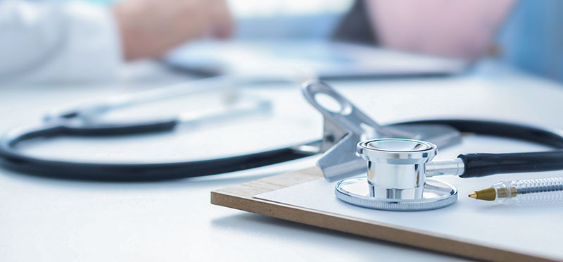 Stethoscope and clipboard sitting on a desk 