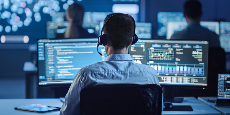 Man wearing a headset looking at a computer screen full of data 