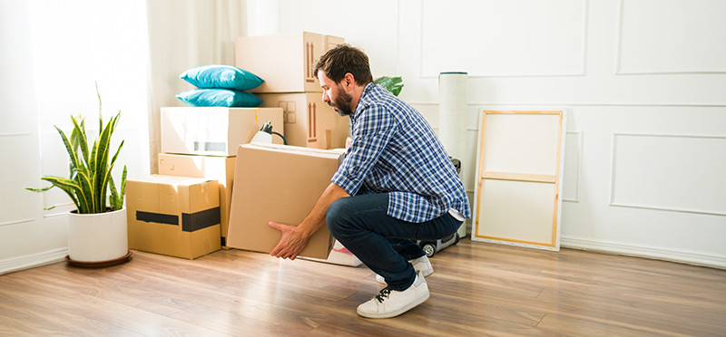 A man bending down to pick up a heavy box
