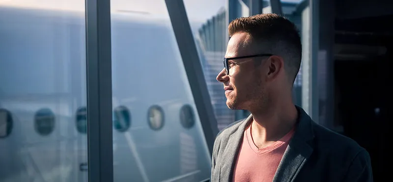 Smiling man looking out the window of an airport 