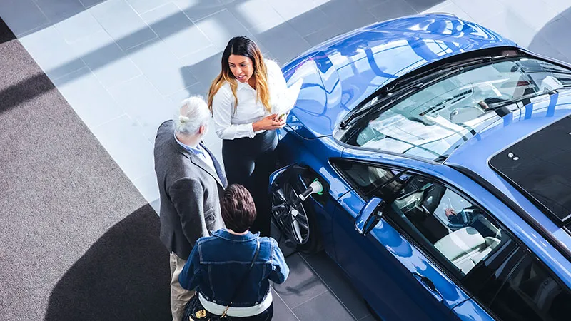 Three people talking beside a car