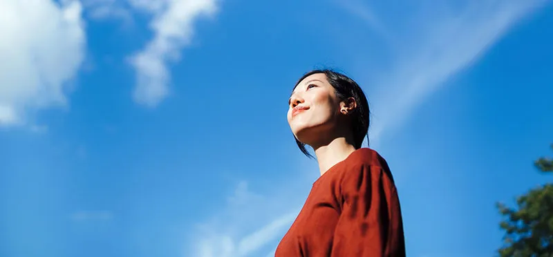 Woman looking up and smiling against a blue sky background