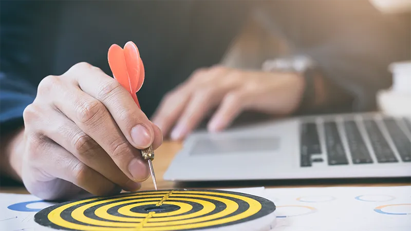 A hand placing a dart onto a target