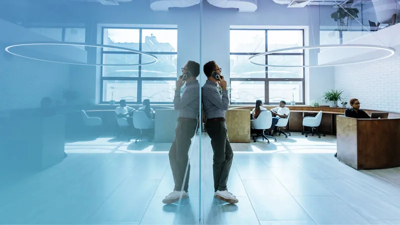 A man standing in the center, leaning against a glass partition