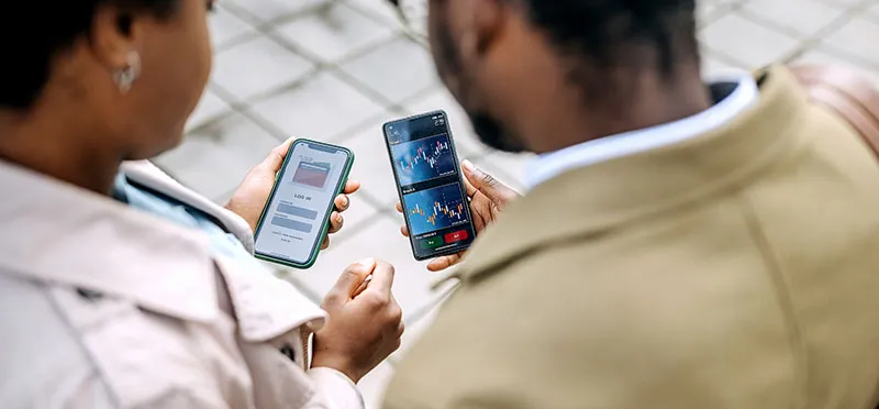 An over-the-shoulder view of two people looking at smartphones