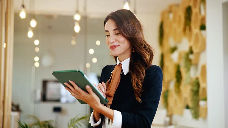 A woman with a smile on her face while looking at her iPad