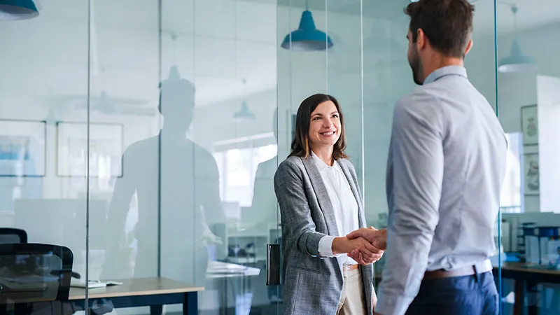 A man and a woman doing a handshake at the office