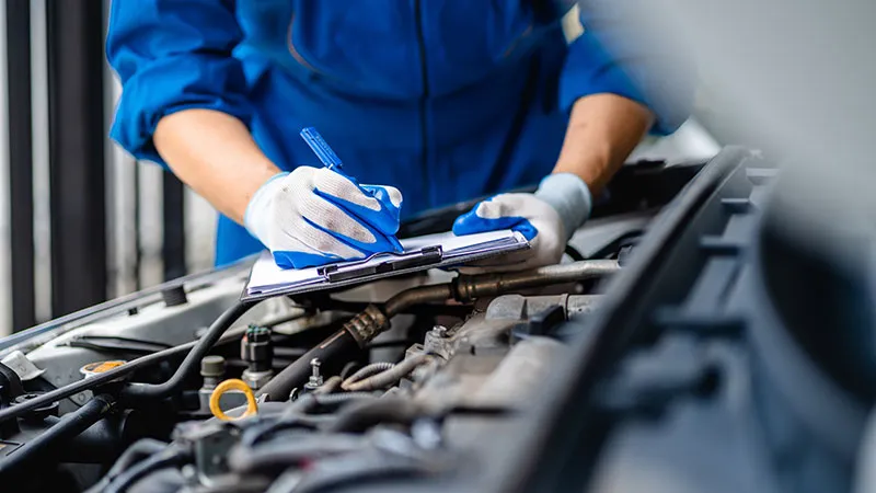 A mechanic holding a pen and a clipboard