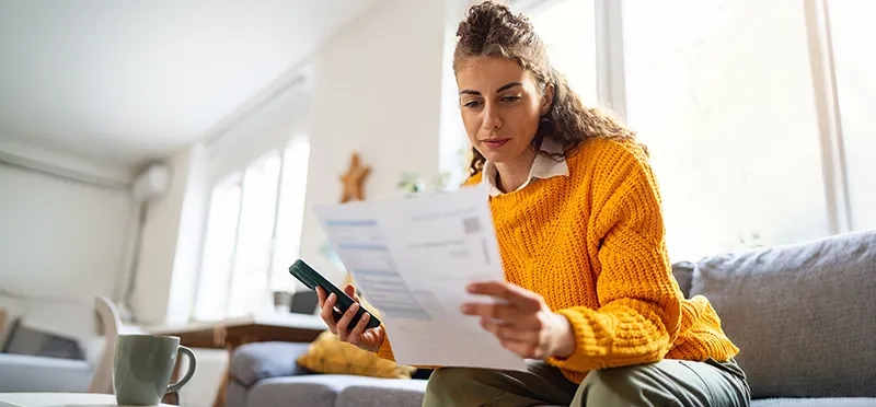 Woman looking at a bill and holding a phone